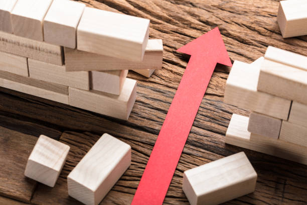 red paper arrow amidst blocks on wooden table - boundary imagens e fotografias de stock