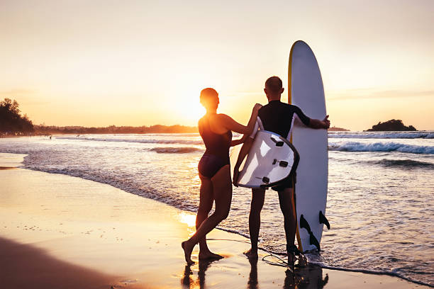 istock Couple surfers stay on sunset ocean beach 922106996