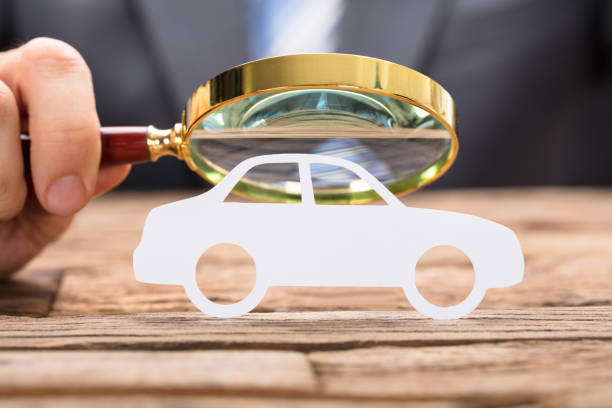 istock Businessman's Hand Examining Paper Car With Magnifying Glass 922107130