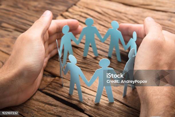 Businessmans Hands Covering Paper Team On Table Stock Photo - Download Image Now - Safety, Support, Protection