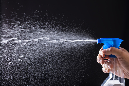 A woman sprays herself with mosquito repellent.