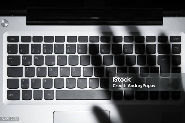 Shadow Of Persons Hand Falling On Laptop Keypad Stock Photo - Download Image Now - Shadow, Above, Computer