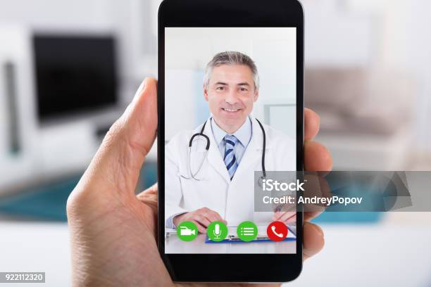 Persona Videoconferencia Con Médico De Smartphone Foto de stock y más banco de imágenes de Doctor - Doctor, Telemedicina, Videollamada