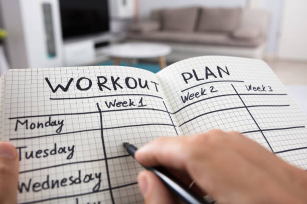 Person Writing Workout Plan In Notebook ripl fitness