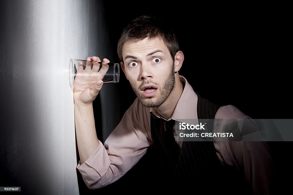 Gut aussehender junger Mann mit Glas auf eavesdrop - Lizenzfrei Belauschen Stock-Foto