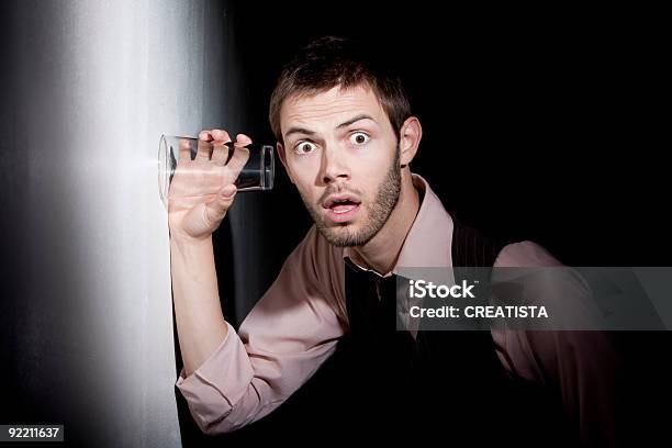 Gut Aussehender Junger Mann Mit Glas Auf Eavesdrop Stockfoto und mehr Bilder von Belauschen - Belauschen, Detektiv, Dunkel