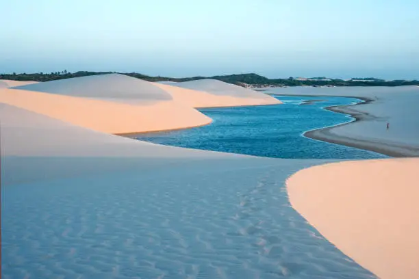 Photo of Lagoons in the desert of Lencois Maranhenses National Park, Brazil, low, flat, flooded land, overlaid with large, discrete sand dunes with blue and green lagoons