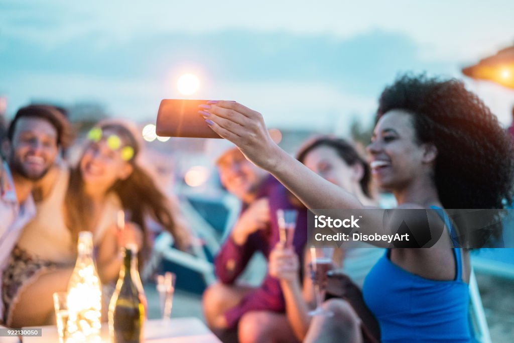 Happy friends taking selfie with smartphone at beach party outdoor - Young people having fun at kiosk bar drinking champagne - Soft focus on mobile cell phone - Youth lifestyle and vacation concept Beach Stock Photo