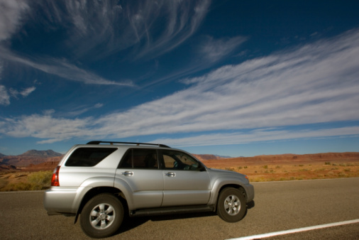 Toyota SUV parked in lay-by in front of snowcapped mountains and lake near Eidsnes and Solavågen in  Alesund, Norway. May 15, 2022