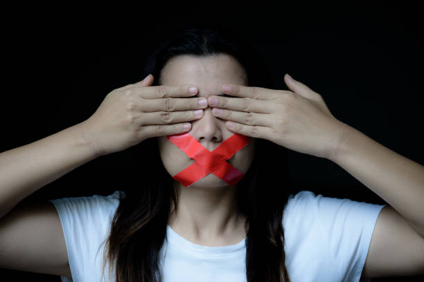 Young woman was wrapping her mount by adhesive tape,  Concept freedom of speech, censorship, freedom of press. International Human Right day. Young woman was wrapping her mount by adhesive tape,  Concept freedom of speech, censorship, freedom of press. International Human Right day. Trafficking stock pictures, royalty-free photos & images