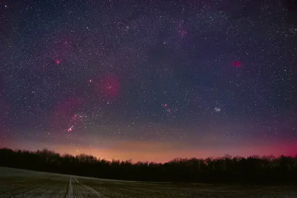 Winter night sky including Barnard’s Loop, the Orion Nebula, the Flame Nebula, the Rosette Nebula, the California Nebula, and the Pleiades as seen from Battenberg in the Palatinate Forest in Germany.