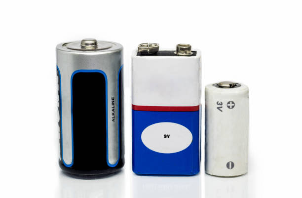 pilhas alcalinas, baterias 9v e 3v, isoladas em um fundo branco com superfície reflexiva - alcalino - fotografias e filmes do acervo