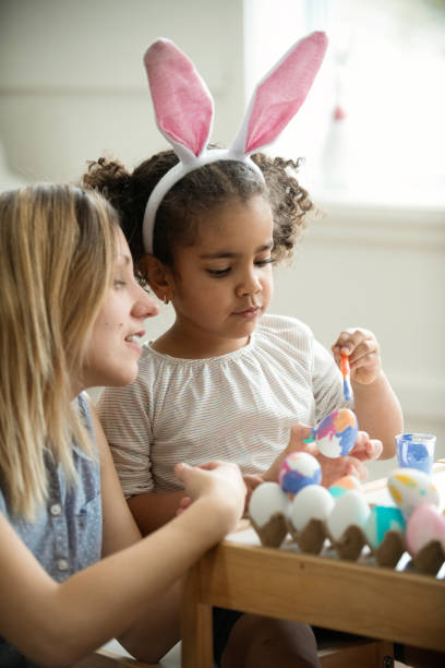 istock Mother and her mixed race daughter painting Easter eggs. 922161408