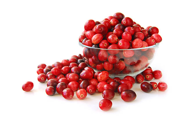 Cranberries overflowing a clear bowl with a white background stock photo
