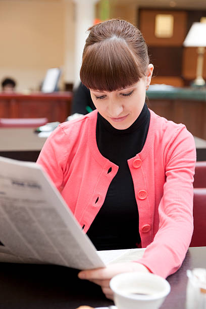 istock Young woman reading newspaper in hotel lobby 92220052