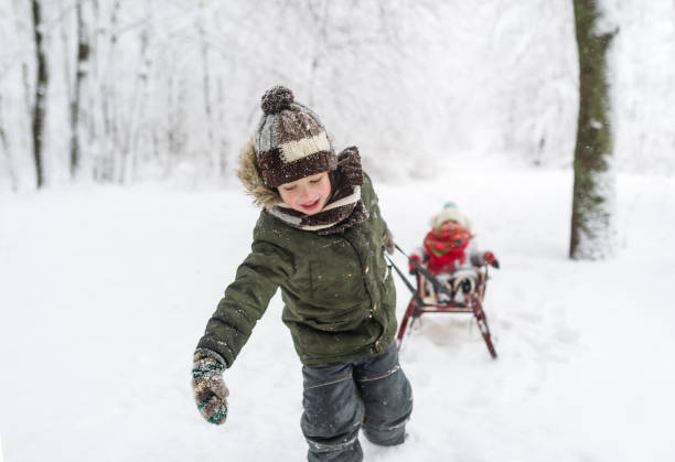 маленькие дети наслаждаются поездкой на санях. детские санки. дети играют на открытом воздухе в снегу. - little boys sled clothing slide стоковые фото и изображения