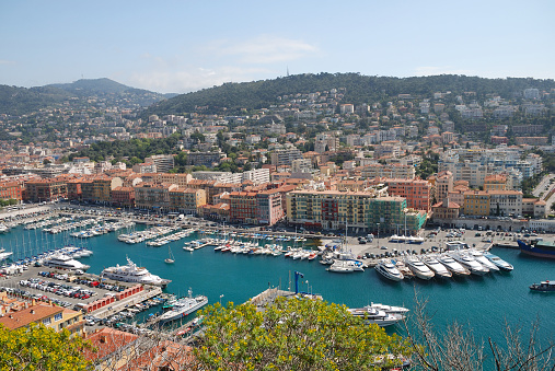 Blue bay with a lot of vessels, launchs and yachts in the middle of Nice, modern buildings among trees in the hills