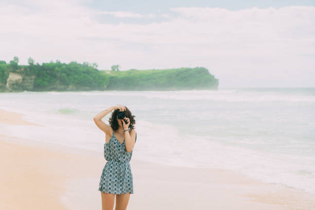 Young Caucasian woman  with camera walking on the beach in Bali