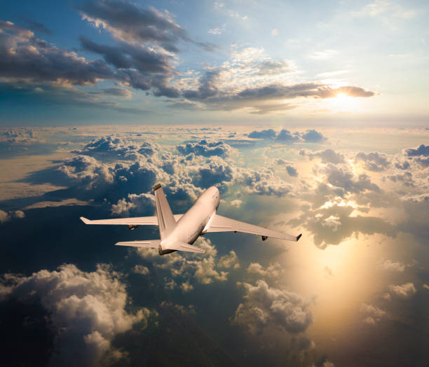 Passenger airplane flying above clouds during sunset