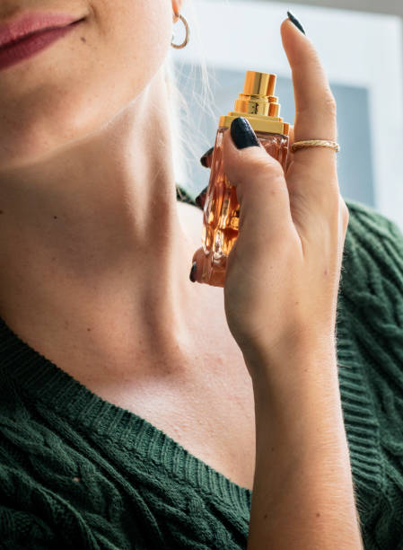 Caucasian woman applying perfume to her neck stock photo