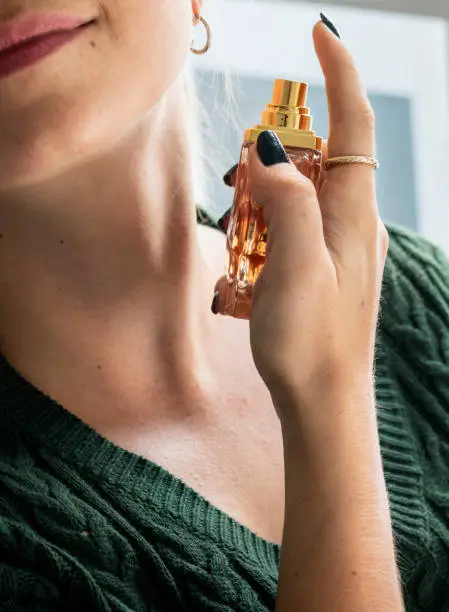 Photo of Caucasian woman applying perfume to her neck