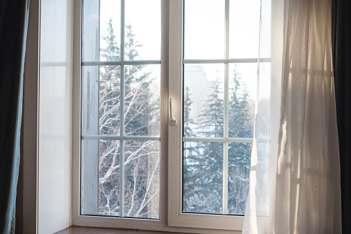 White window frame with curtain blowing by wind, winter scenic view in the morning