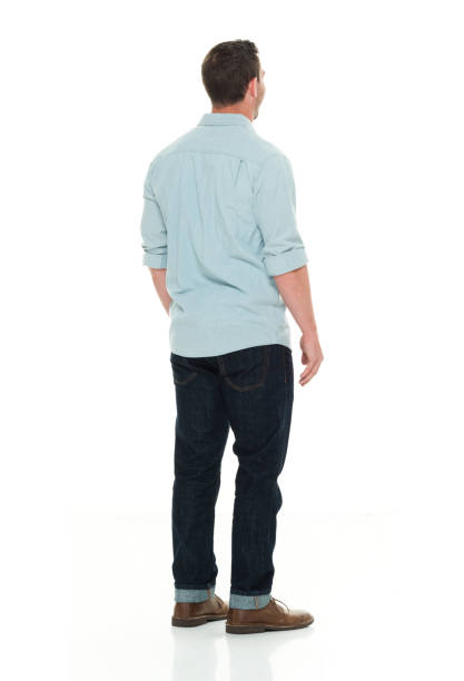 Attractive Asian man wearing blue shirt smiling with arms crossed while standing over white background