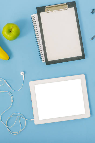 istock Home office workspace. Office table with tablet, headphones, fruit, pencil, notepad and clipboard. Flat lay 922289728