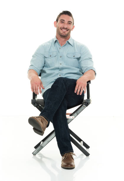 hombre guapo sentado en la silla del director - silla de director fotografías e imágenes de stock