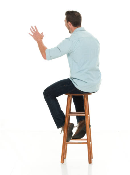 istock Charming happy man seated on wood stool waving 922304914