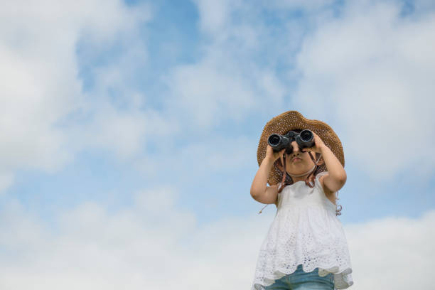 Little girl is watching far away with binoculars