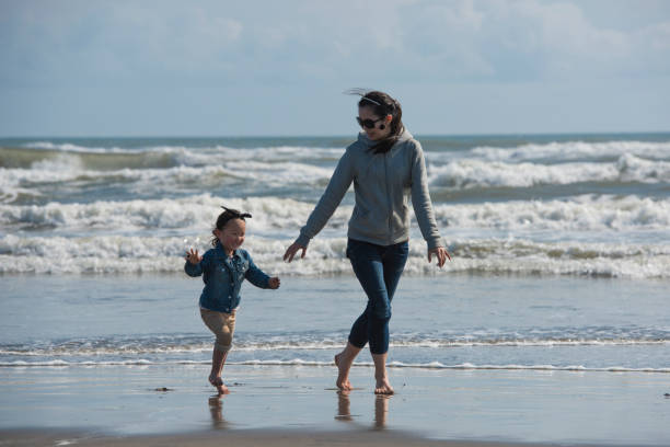 Mother and child playing at tropical beach. Family sea summer vacation. Mom and kid, toddler boy, play in the water. Ocean and water fun for parent and kids. Fit and healthy family at exotic beach