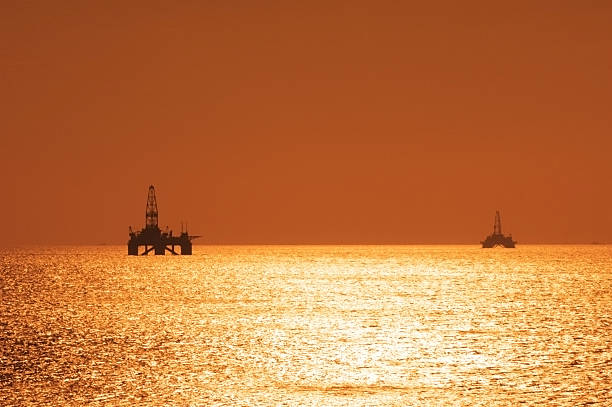 два offshore oil оснастки во время заката в каспийском se - manufacturing equipment energy color image nobody стоковые фото и изображения