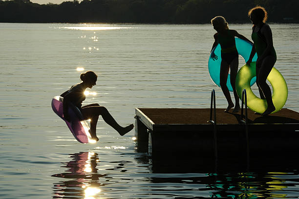 crianças pulando fora swimraft - inner tube swimming lake water - fotografias e filmes do acervo