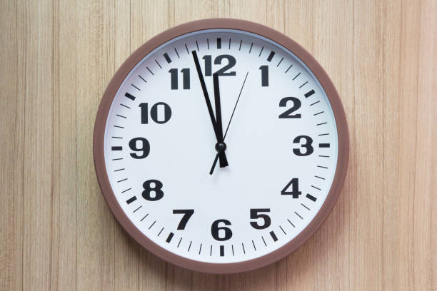istock brown and white clock shown almost mid day or mid night time on light wooden wall, concept : countdown for new year 922335668