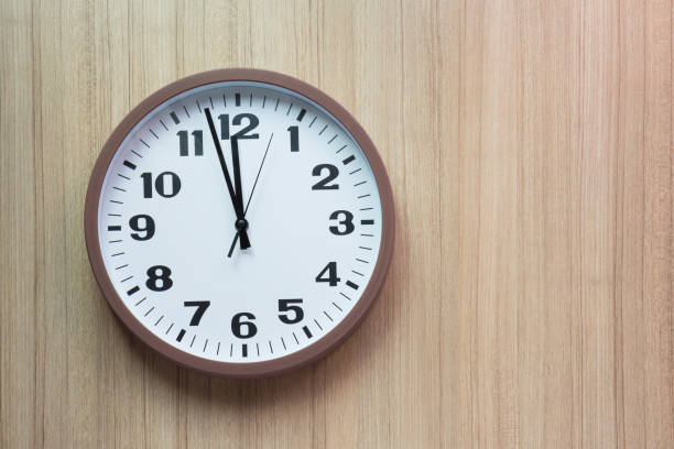 istock brown and white clock shown almost mid day or mid night time on light wooden wall, Free copy space for text, concept : countdown for new year 922335672