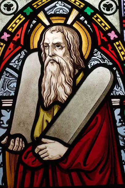 Detail of Victorian stained glass church window depicting Moses with the tablets of covenant in his arms, interestingly without text, means he is pictured before climbing Mount Sinai.