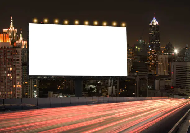 Blank billboard on the highway during the twilight with city background with clipping path on screen.- can be used for displaying your products or promotional