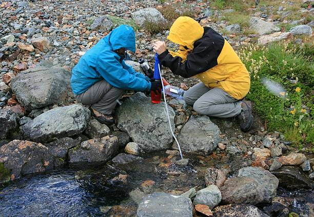 Women Filtering Water from Creek  garibaldi park stock pictures, royalty-free photos & images