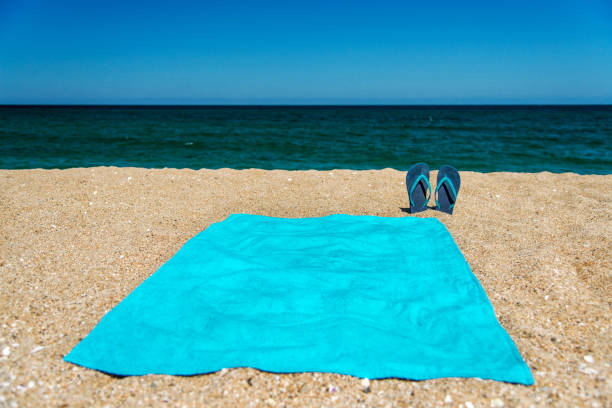 istock Blue sandal flip flop and towel on yellow sand 922344670