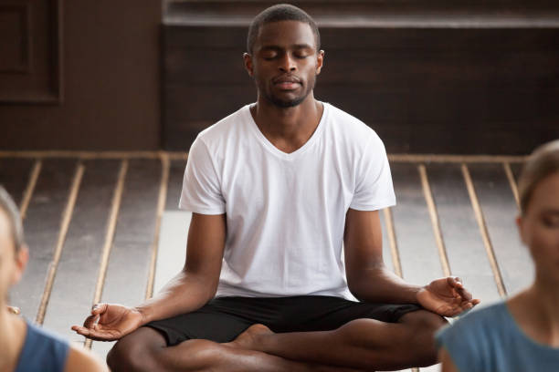 istock Young sporty black man sitting in Sukhasana exercise 922344924