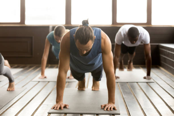 gruppe von sportliche menschen in plank-pose - good posture yogaclass lifestyles sport stock-fotos und bilder