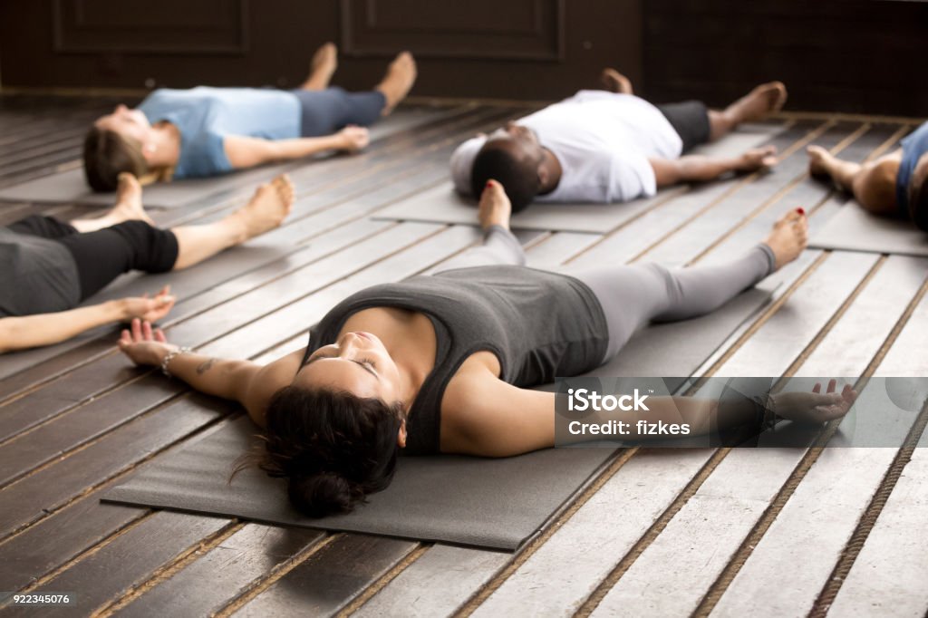 Gruppo di sportivi a Savasana posa - Foto stock royalty-free di Yoga