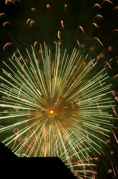 Fireworks explode beyond building in silhouette