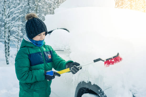 istock boy is cleaning the car from the snow 922359736