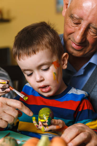 istock Grandfather with grandson painting eggs for Easter. 922359758