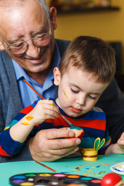 istock Grandfather with grandson painting eggs for Easter. 922362272