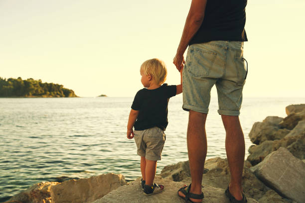 istock Father and son back silhouettes walking by the sea. 922362602