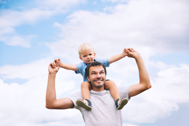 istock Father carrying his son on his back with raised arms up against the sky. 922362786