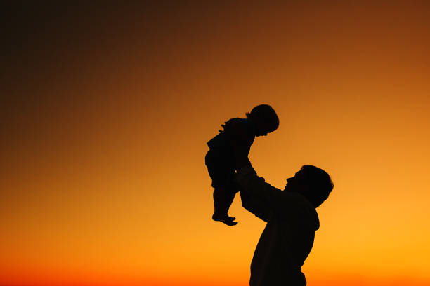 istock Father and son silhouettes at sunset sky. 922362862